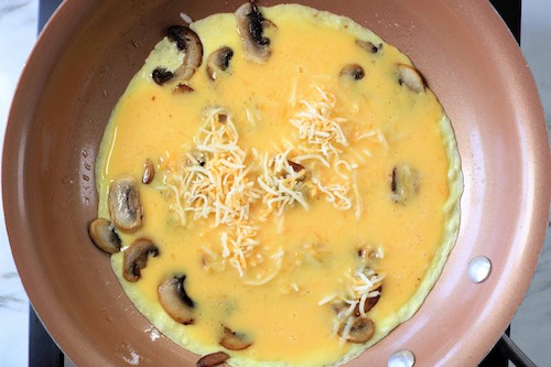 eggs with mushrooms and cheese in a copper pan