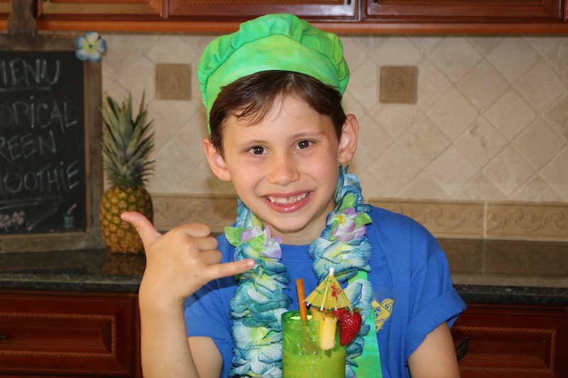 tropical green smoothie with boy drinking