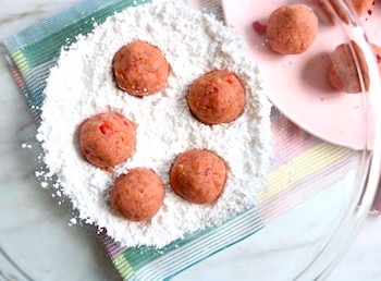 strawberry cake balls in powdered sugar bowl