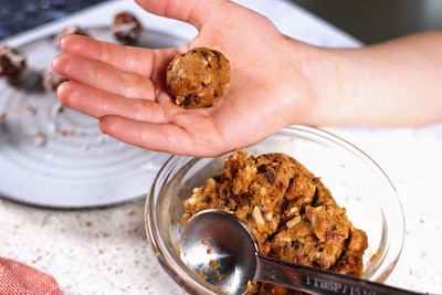 boys hands holding rolled pumpkin protein-ball