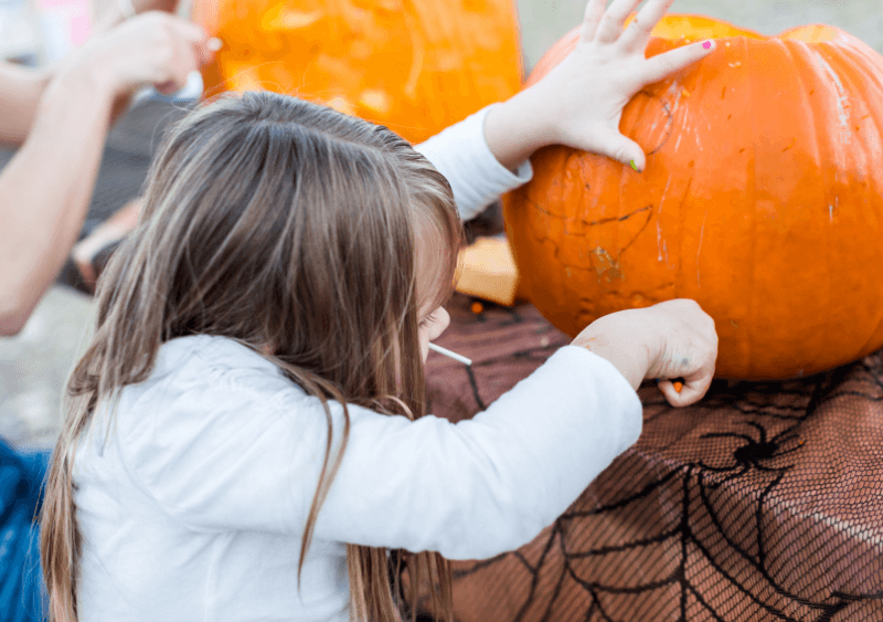 child carving pumpkin using tools