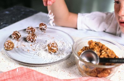boy sprinkling coconut over pumpkin protein-balls